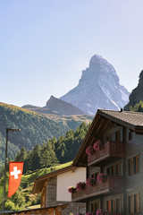 Obraz premium Traditional Chalet in Zermatt with Matterhorn peak with Swiss flag