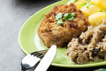 Fried pork schnitzel served with boiled potatoes and fried sauer