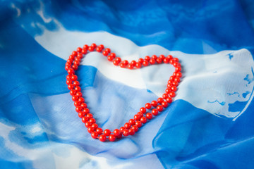 red heart of beads on a background of blue silk