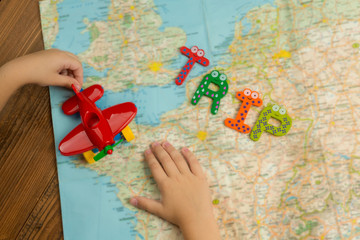 Trip by toy plane around the world with kids. Top view with child hands. Travel theme items. 