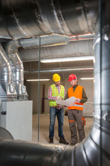 Workers making final touches to HVAC system. HVAC system stands for heating, ventilation and air conditioning technology. Team work, HVAC, indoor environmental comfort concept photo.