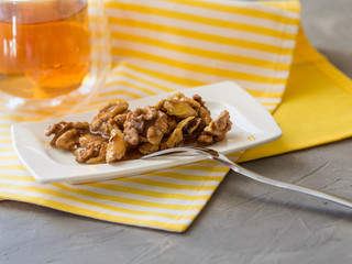 Honey in white jar, nuts, top view cup of tea in glass