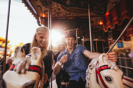 Young couple having fun on carousel