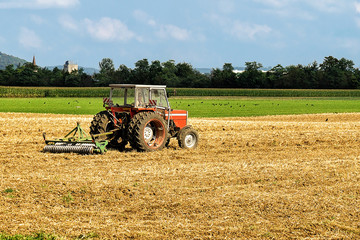 Fototapeta premium Tractor with plough doing agricultural seasonal work in field