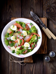 Salad from slightly salted salmon, boiled potatoes, quail eggs with cucumber and radish.