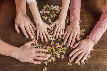 Close-up partial view of family with one child playing with puzzles on table