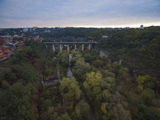 Fototapeta na wymiar Aerial shot of the canyon of the Smotrych River towards the Novoplanivskyi Bridge in Kamianets-Podilski Ukraine. The shot is taken in autumn with the canyon trees looking colourful