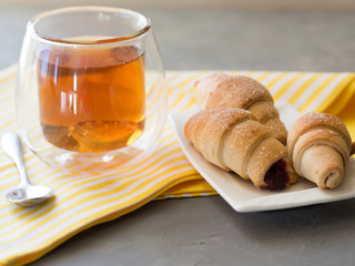 Fresh bagel, hot cup of tea and spoon on a yellow towel