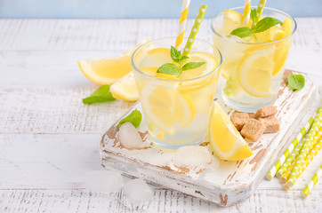 Cold refreshing summer drink with lemon and mint on wooden background.