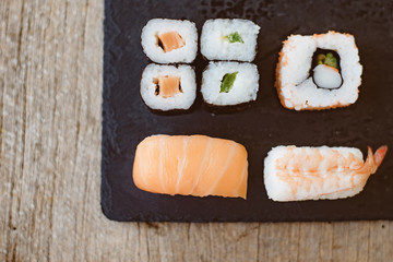 Sushi Set sashimi and sushi rolls served on stone slate