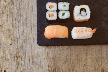 Sushi Set sashimi and sushi rolls served on stone slate