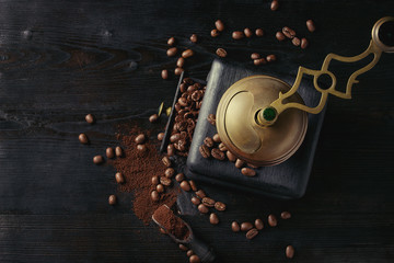 Roasted coffee beans and grind coffee in wood box with vintage coffee grinder and scoop over black wooden burnt background. Top view with space.