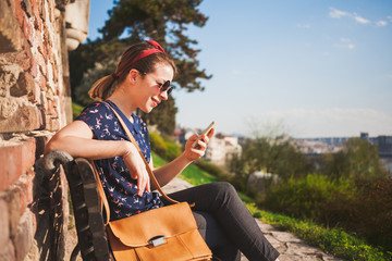 Young woman sitting in the park using smartphone