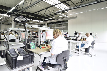 Frauen bei der Montage von elektronischen Bauteilen in einer Fabrik für Microelektronik // Women...