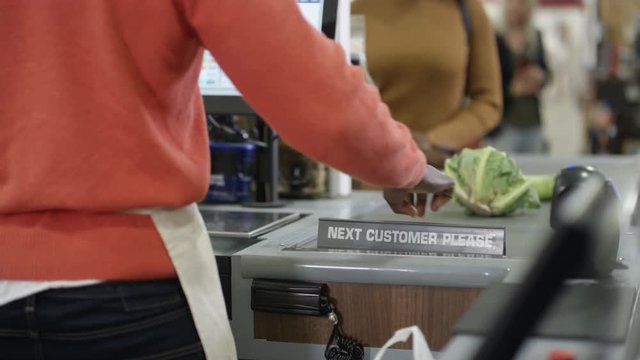  Friendly cashier taking payment from a customer at grocery store checkout