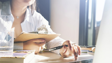 Photo of young student working on a laptop at home on a sunny day. Photo with the focus on female's...