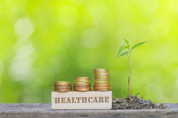 HEALTHCARE WORD Golden coin stacked with wooden bar on shallow DOF green background.