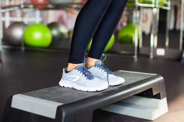 Close Up, girl performs step cardio with dumbbells in a gym