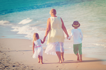 grandmother with kids- little boy and girl- walk at beach