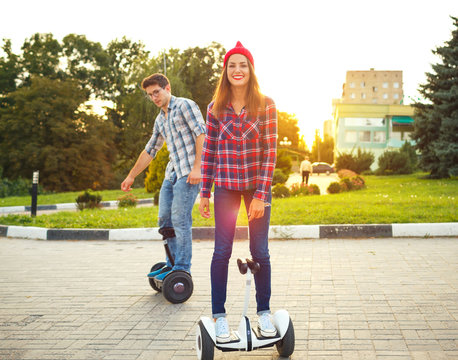 Young couple riding hoverboard - electrical scooter, personal eco transport, gyro scooter, smart balance wheel