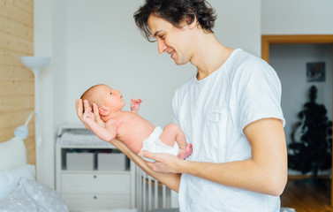 Close-up portrait of happy young father hugging and kissing his sweet adorable newborn child. Fatherhood concept image