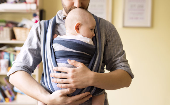 Father with baby son in sling at home