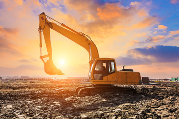 excavator in construction site on sunset sky background