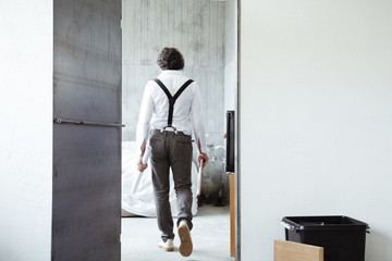 Back view of architect with sketch book and construction plan at construction site