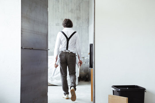 Back view of architect with sketch book and construction plan at construction site