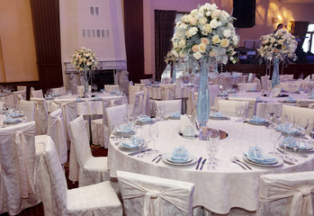 luxury decorated tables at rich wedding reception. stylish arrangements of flowers and jewels on table in glass vase, dish and glasses on tablecloth. expensive catering. space for text.