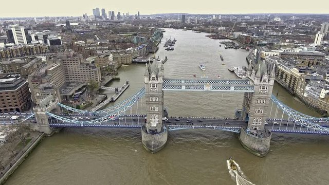 Aerial Shot of Flying Over Tower Bridge and River Thames in London, UK feat. Skyscrapers and Business Office Buildings in the Background with Boats and Car Transportation Vehicles in 4K Ultra HD