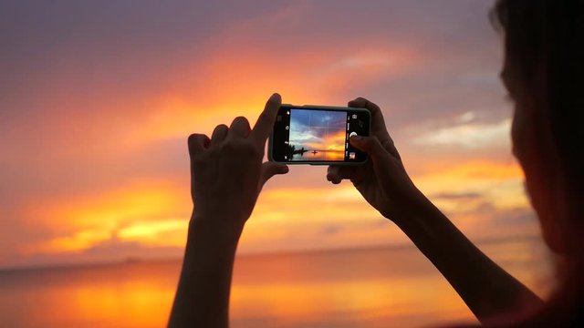 Young Mixed Race Girl Taking Photo of Beautiful Sunset Using Mobile Phone. HD Slowmotion. Thailand.