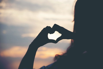 Fototapeta na wymiar Silhouette hand making heart with sunset