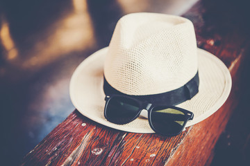 Sunglasses on hat on bench, vintage filter, travel concept