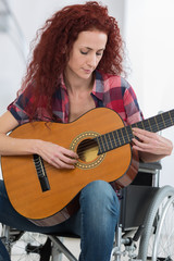 disabled woman playing guitar in her living room