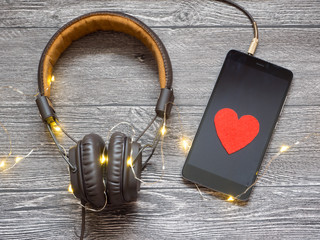 the heart symbolizes the love of music. headphones connected to the smartphone .