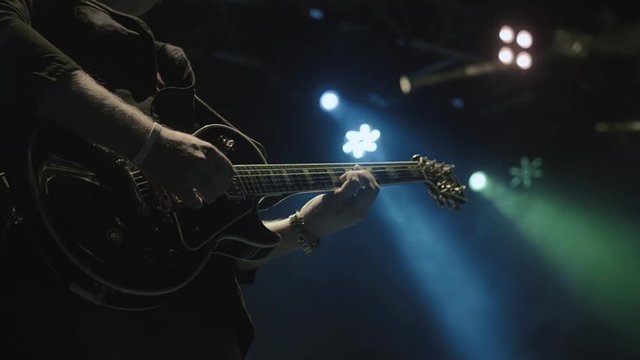Silhouette of guitar player on stage. Dark background, smoke, spotlights
