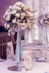 luxury wedding decor with flowers and glass vases and number of setting on round tables. arrangements of decorations at wedding reception. expensive catering. space for text