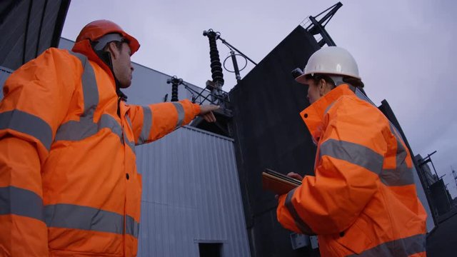  Long shot of team of engineers standing on platform at a power plant. 