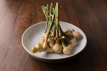 Fresh Ginger Root with stem on wooden background