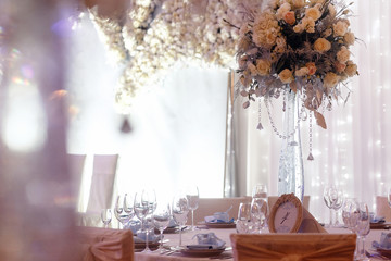 luxury wedding decor with flowers and glass vases and number  of setting on round tables. arrangements of decorations with stones jewels at wedding reception. expensive catering. space for text