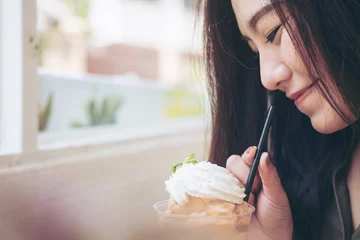 Photo sur Plexiglas Milk-shake A beautiful woman drinking Thai tea milk shake and whipped cream on the top with straw in vintage cafe