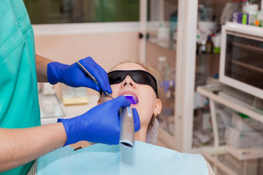 The dentist uses a dental UV lamp on the patient's teeth