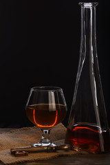 glass, carafe with cognac, whiskey and key on wooden table