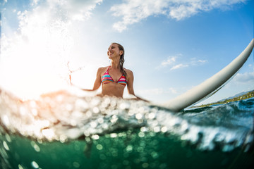 Young woman having fun in the ocean with surfboard
