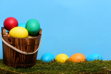 painted easter colorful eggs in wooden bucket with green moss