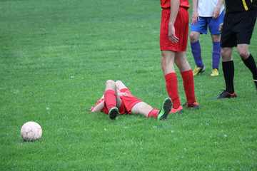 Injured player at the football match lying on the grass