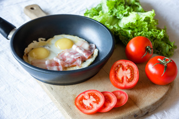 Scrambled eggs and bacon on frying pan on table close-up