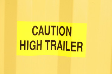 Schild Caution high Trailer auf einem gelben Container