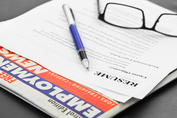 Closeup of resume with pen and glasses on the table with newspaper